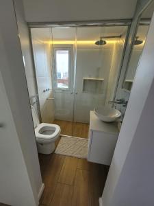 a white bathroom with a toilet and a sink at Nuevo estudio al mar con cochera in Mar del Plata