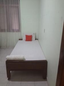 a bed in a room with a red pillow on it at Osheen Family Guest House in Polonnaruwa