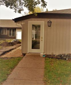 una pequeña casa con una puerta blanca y una acera en The Red 6, en Grand Forks