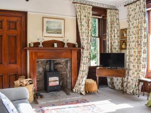 a living room with a fireplace and a television at Gleneffock Farmhouse in Tarfside
