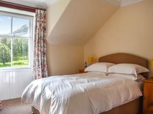 a bedroom with a bed and a window at Gleneffock Farmhouse in Tarfside