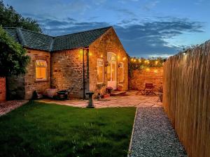 a garden with a stone house with lights on it at Himba Cottage - Uk44767 in Ripon