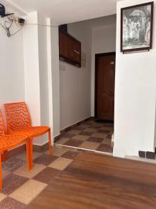 um quarto vazio com uma cadeira laranja e uma porta em MPS Saai Residency em Tiruvannamalai