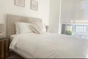 een wit bed met witte kussens en een raam bij YAMA Luxury Condo 2B2B FreeParking in Markham