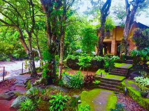 a garden in front of a house with trees at Heritage Belihuloya Resort in Belihul Oya