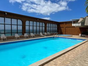 uma grande piscina com cadeiras e um edifício em Apartamento com vista da praia da Costa 615 em Vila Velha