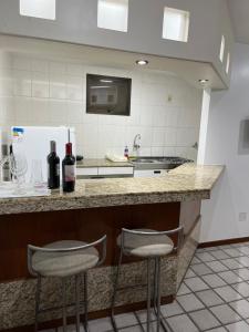 uma cozinha com dois bancos de bar e um balcão com garrafas de vinho em Apartamento com vista da praia da Costa 615 em Vila Velha