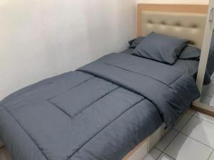 Cama en habitación con sábanas y almohadas azules en Jarrdin Apartment by RumahKu, en Bandung
