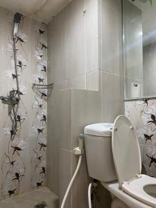 baño con aseo con mariposas en la pared en Jarrdin Apartment by RumahKu, en Bandung