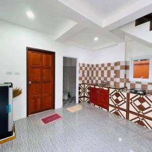 a kitchen with a brown door and a red object on the floor at Phujhaofa villa club ( ไสยวน) in Ban Saiyuan (1)