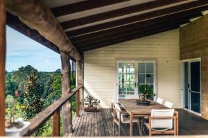 a porch with a wooden table and chairs on a house at The Tree House Bellingen in Thora