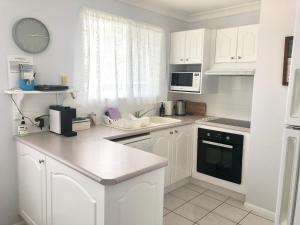 a kitchen with white cabinets and a counter top at Bayz on the River in Maroochydore