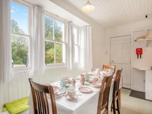 comedor con mesa, sillas y ventanas en Inverglen Farm, en Strachur