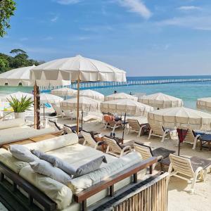 una playa con sillas y sombrillas y el océano en Sawasdee Coco, en Ko Samed