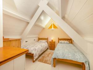 a attic bedroom with two beds and a table at Penpompren in Blaenpenal