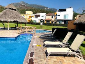 曼萨尼约Casa Completa en Real del Country Alberca y Playa的一个带两把椅子和遮阳伞的游泳池