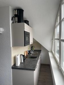 a white kitchen with a sink and a microwave at Ferienwohnungen Ryck Blick in Greifswald