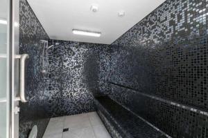 ein schwarz gefliestes Bad mit einem WC und einer Dusche in der Unterkunft Oceanus Luxe Beachfront Bokarina in Kawana Waters