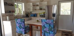eine Küche mit einem Kühlschrank und einem Tisch mit Stühlen in der Unterkunft Are Tamareni 2BR Beach Cottage or River Studio in Avarua