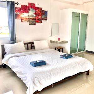 MY HOME Hotel - Phutthamonthon 4 Road, near Mahidol University Salaya في Ban Krathum Lom: غرفة نوم بسرير ابيض كبير عليها طياتين ازرق