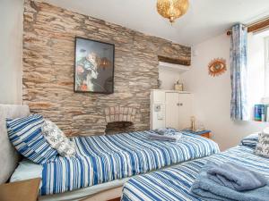 two beds in a room with a stone wall at Gypsett in Polruan