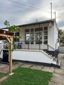 a white house with a porch and a balcony at Sparkling Time Apartman in Hajdúszoboszló