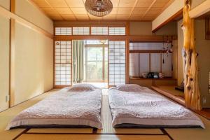 two beds in a room with a window at 一組限定の貸切空間 Guest House Engiya in Matsumoto