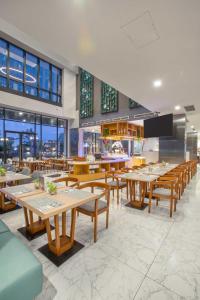 a restaurant with wooden tables and chairs and windows at THE 1O1 Jakarta Airport CBC in Tangerang