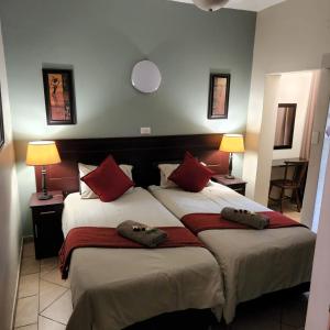 a bedroom with two beds with red pillows at Shonalanga Lodge in St Lucia