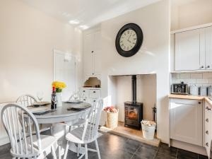 uma cozinha com mesa e cadeiras e um relógio na parede em Veras Cottage em Edale