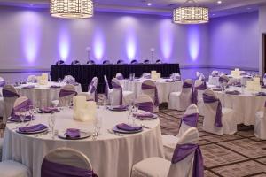 un salón de banquetes con mesas blancas, sillas y luces en Marriott East Lansing at University Place, en Lansing