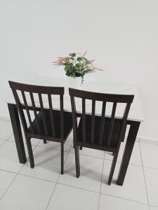 una mesa con dos sillas y un jarrón de flores en HOMESTAY CAHAYA PUTERI, en Tangga Batu