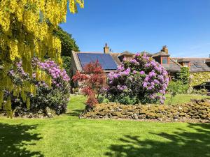 a garden with flowers and a stone wall at Netherley Grange in Peterculter