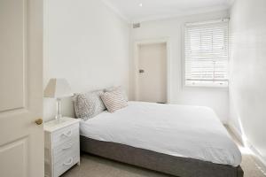 a white bedroom with a bed and a window at Balmoral Apt unbelievable views 1min walk to beach in Sydney