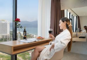 a woman sitting at a table with a glass of wine at KOVA Diamond Hotel Da Nang in Danang