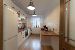 a kitchen with white cabinets and a wooden counter top at Apartament przy Czarnej Bramie in Kłodzko