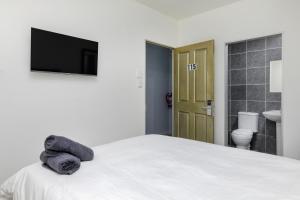 um quarto com uma cama e uma televisão na parede em Inn & Out Express Sea Point em Cidade do Cabo