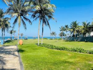 einen Weg durch einen Park mit Palmen und dem Meer in der Unterkunft Danang Amazing Ocean Villas in Đà Nẵng