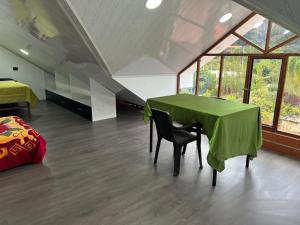 キトにあるCasa de Campo Guayllabambaの緑のテーブル、ベッド、窓が備わる客室です。