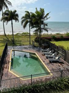 a swimming pool with lounge chairs and the beach at ABSOLUTE BEACHFRONT BLISS - NEWELL BEACH - 10 Metres to the Ocean in Newell Beach