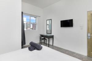 a room with a bed with a desk and a television at Inn & Out Express Sea Point in Cape Town