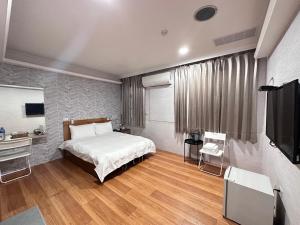 um quarto com uma cama e uma televisão de ecrã plano em 町宿溫泉旅館 em Jiaoxi