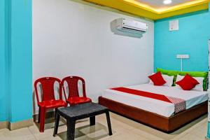 a bedroom with a bed and two red chairs at OYO Flagship Hotel Daffodil Lodging and Boarding in Jānla