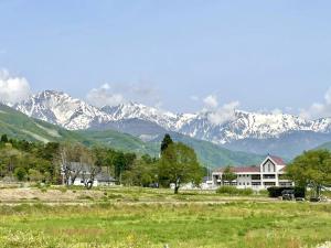 una casa en un campo con montañas en el fondo en HAKUBA House LuckyStar5 next to shuttle bus station ,711 ,restaurants Modern Chalet, en Hakuba