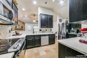 a large kitchen with black cabinets and stainless steel appliances at Luxury Retreat - Pool - Game Lounge - BBQ & Patio in San Antonio