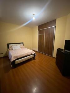a bedroom with a bed and a wooden floor at Garzonier in Cochabamba