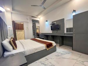 德拉敦Hotel Embassy的一间带床和电视的酒店房间