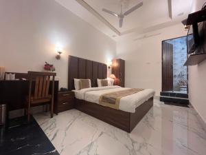 een slaapkamer met een groot bed, een bureau en een tafel bij Hotel Embassy in Dehradun