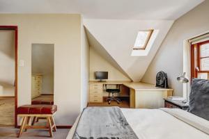 an attic bedroom with a bed and a desk at Le Arc Manor House in Franschhoek