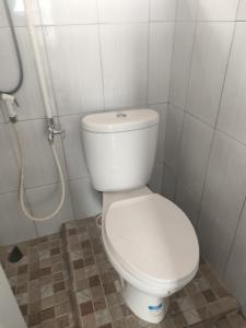 a white toilet in a bathroom with a shower at Kutnalek Surf Camp Siberut in Masokut
